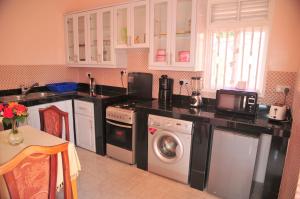 a kitchen with a sink and a washing machine at Victoria Lake View Guesthouse & Safaris in Entebbe