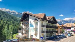 a building on the side of a street with mountains at Hotel Fanes Suite & Spa in Moena