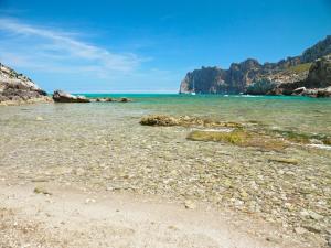 a beach with rocks and the ocean on a clear day at Hotel Cala Sant Vicenç - Adults Only in Cala de Sant Vicenc