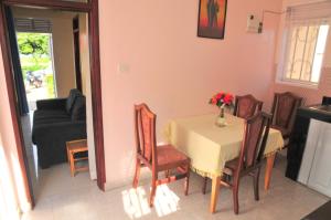 a dining room table and chairs with a vase of flowers on it at Victoria Lake View Guesthouse & Safaris in Entebbe