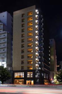 a tall building with illuminated windows at night at BRENZA HOTEL in Kobe