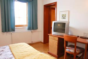 a bedroom with a desk with a tv and a bed at Guest House Arvaj in Kranj