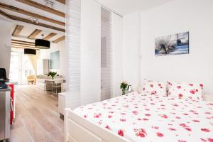 a white bedroom with a white bed with red flowers at GH Amsterdam in Amsterdam