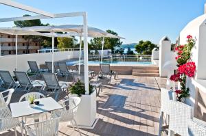 a patio with white tables and chairs and umbrellas at BQ Bulevar Peguera- Adults Only in Paguera