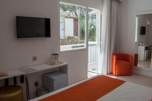 a room with a tv and a desk and a window at BQ Bulevar Peguera- Adults Only in Paguera
