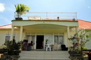 a house with a balcony with a table and chairs at Victoria Lake View Guesthouse & Safaris in Entebbe
