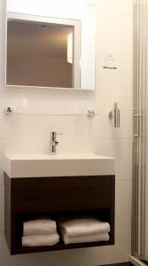 een badkamer met een wastafel, een spiegel en handdoeken bij Fletcher Hotel-Restaurant Het Witte Huis in Amersfoort