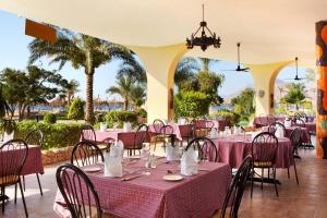 um restaurante com mesas e cadeiras cor-de-rosa e palmeiras em TIME Coral Nuweiba Resort em Nuweiba