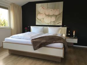 a bedroom with a large white bed with a painting on the wall at Pension Landart in Wangerland