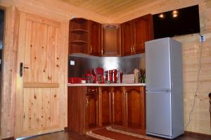 ウストロニエ・モルスキエにあるDomek drewniany modrzewiowy w Ustroniu Morskimのキッチン(木製キャビネット、白い冷蔵庫付)