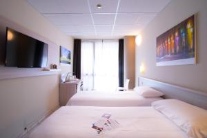 a hotel room with two beds and a flat screen tv at Best Quality Hotel Politecnico in Turin