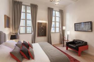 a bedroom with a bed and a chair and windows at Maison Du Collectionneur in Aix-en-Provence