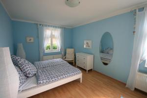 a bedroom with blue walls and a bed and a window at Ferienhaus Schwalbe Seebad Lubmin in Lubmin