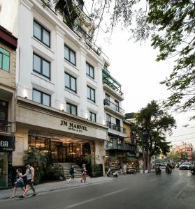 a group of people crossing a street in front of a building at JM Marvel Hotel & Spa in Hanoi