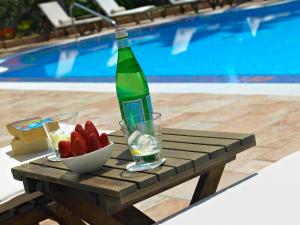a bottle of water and a bowl of strawberries on a table by a pool at Hotel Cala Sant Vicenç - Adults Only in Cala de Sant Vicenc