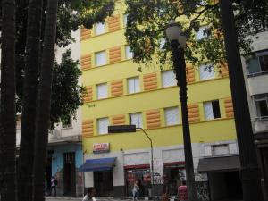 un edificio amarillo en una calle de una ciudad en Hotel Moraes a 10 minutos da 25 de Março,Brás,Bom Retiro,a 2 minutos do Mirante Sampa Sky e pista de Skate Anhangabaú, en São Paulo