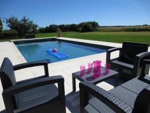 a pool with two chairs and a table with glasses on it at Le Grand Coudreau in Nazelles