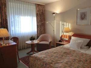 a hotel room with a bed and a chair and a window at Hotel Heuberg in Norderstedt