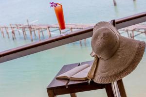 a straw hat sitting on a bench next to a drink at Enjoy Beach in Bophut