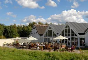 een groep mensen die aan tafels buiten een gebouw zitten bij Sankt Helene Feriecenter Tisvildeleje in Tisvildeleje