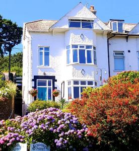 a white house with flowers in front of it at Schooner Point Guest House in Looe