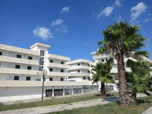 deux palmiers devant un bâtiment blanc dans l'établissement Residenza Arene, à Gallipoli