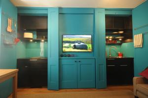 a kitchen with a blue door with a tv on it at Mulberry cottage in Cheltenham