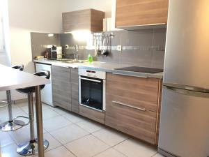 a kitchen with stainless steel appliances and wooden cabinets at T2 Hyper centre clim,WIFI in Hyères