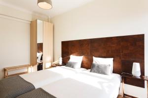 een slaapkamer met een groot wit bed met een houten hoofdeinde bij WHome | Anjos Premium Apartment #8 in Lissabon