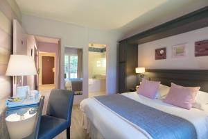 a bedroom with a bed and a desk and a chair at LOGIS Hôtel & Restaurant - LENSOTEL in Lens