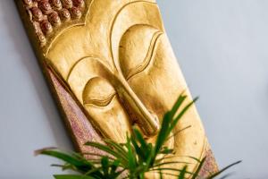 a gold buddha statue next to a plant at Enjoy Beach in Bophut