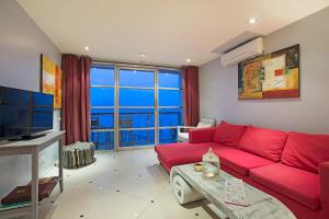 a living room with a red couch and a large window at Enjoy Beach in Bophut