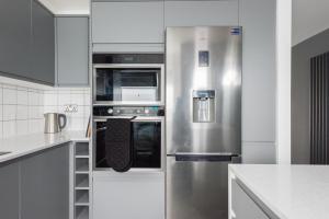 - un réfrigérateur en acier inoxydable dans une cuisine avec des placards blancs dans l'établissement The Waterloo Residence, à Londres