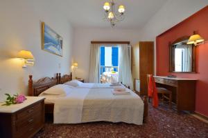 a bedroom with a bed and a desk and a window at Galini Hotel in Mikonos