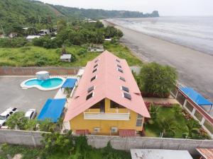 a yellow house with a pink roof next to the beach at Hotel Soberao in Esmeraldas