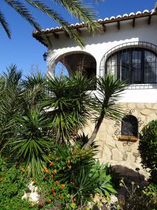 une maison avec des palmiers devant elle dans l'établissement Casa Andalus Holiday Villa, à Jávea