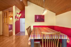 a dining room with a table and a red couch at AlpinAppartements Stöckl in Partenen