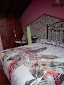 a bedroom with a large bed with a stone wall at La Ería de Colombres in Colombres