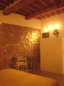 ein Schlafzimmer mit einer Steinmauer mit einem Tisch und einem Stuhl in der Unterkunft Rinathos Guesthouse in Arezzo