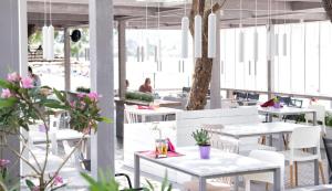 un ristorante con tavoli bianchi, sedie bianche e piante di Gaea Gardens Studios & Villas a Pétra
