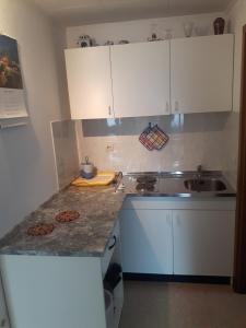 cocina con armarios blancos y encimera en Apartma Bel, en Žaga