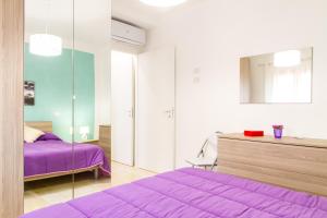 a bedroom with a purple bed and a mirror at Vanni House 68 in Cefalù