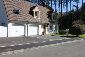 une maison blanche avec deux portes de garage dans une rue dans l'établissement La Tonnelle, à Hardelot-Plage