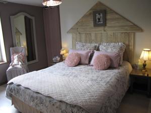 a bedroom with a large bed with pink pillows at L'Ecurie in La Pommeraye