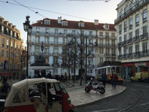 リスボンにあるLisbon Fragrancesの建物やスクーター、トラムが並ぶ街並み