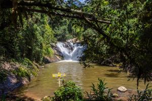 a waterfall in a river with a sign in front of it at Pousada Cabanas no Mundo in Gonçalves