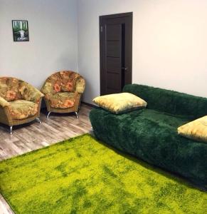 a living room with two couches and a green rug at Двухкімнатна студія in Chernihiv