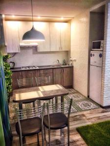 eine Küche mit einem Tisch und Stühlen sowie einem Kühlschrank in der Unterkunft Двухкімнатна студія in Tschernihiw