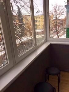 asiento junto a la ventana con 2 taburetes y 2 ventanas en Двухкімнатна студія, en Cherníhiv