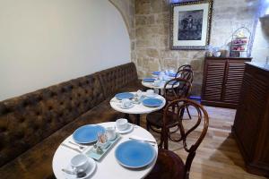 a dining room with two tables with blue dishes on them at The Burrow Guest House in Tarxien